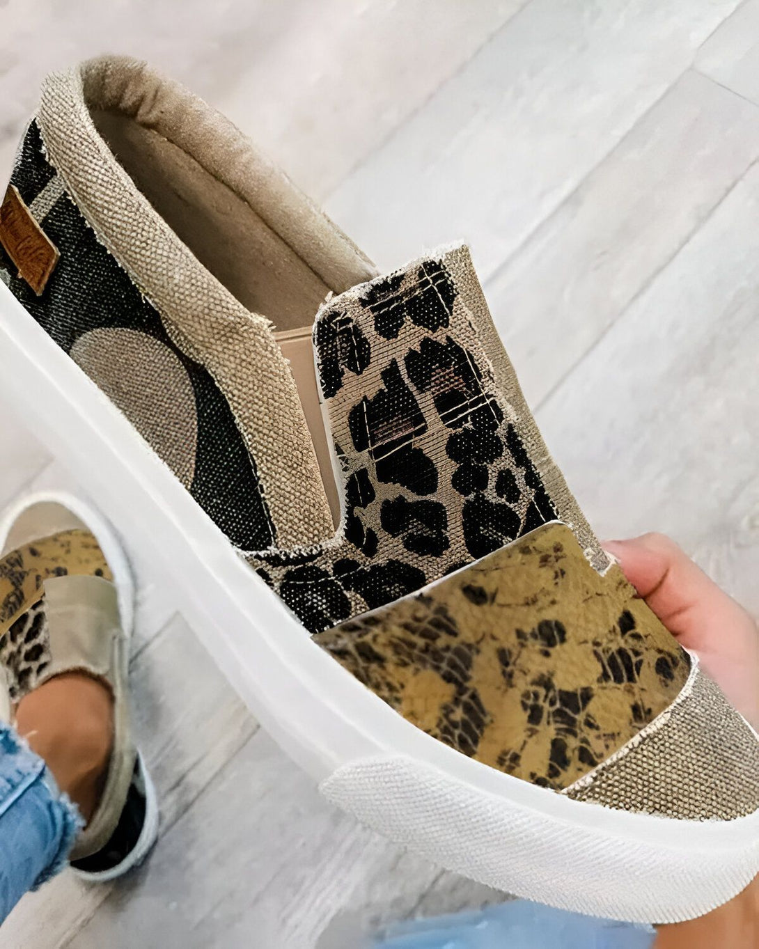 Une image d'une paire de chaussures slip-on avec un motif léopard et un empiècement en cuir de serpent. Les chaussures sont de couleur marron et blanche.