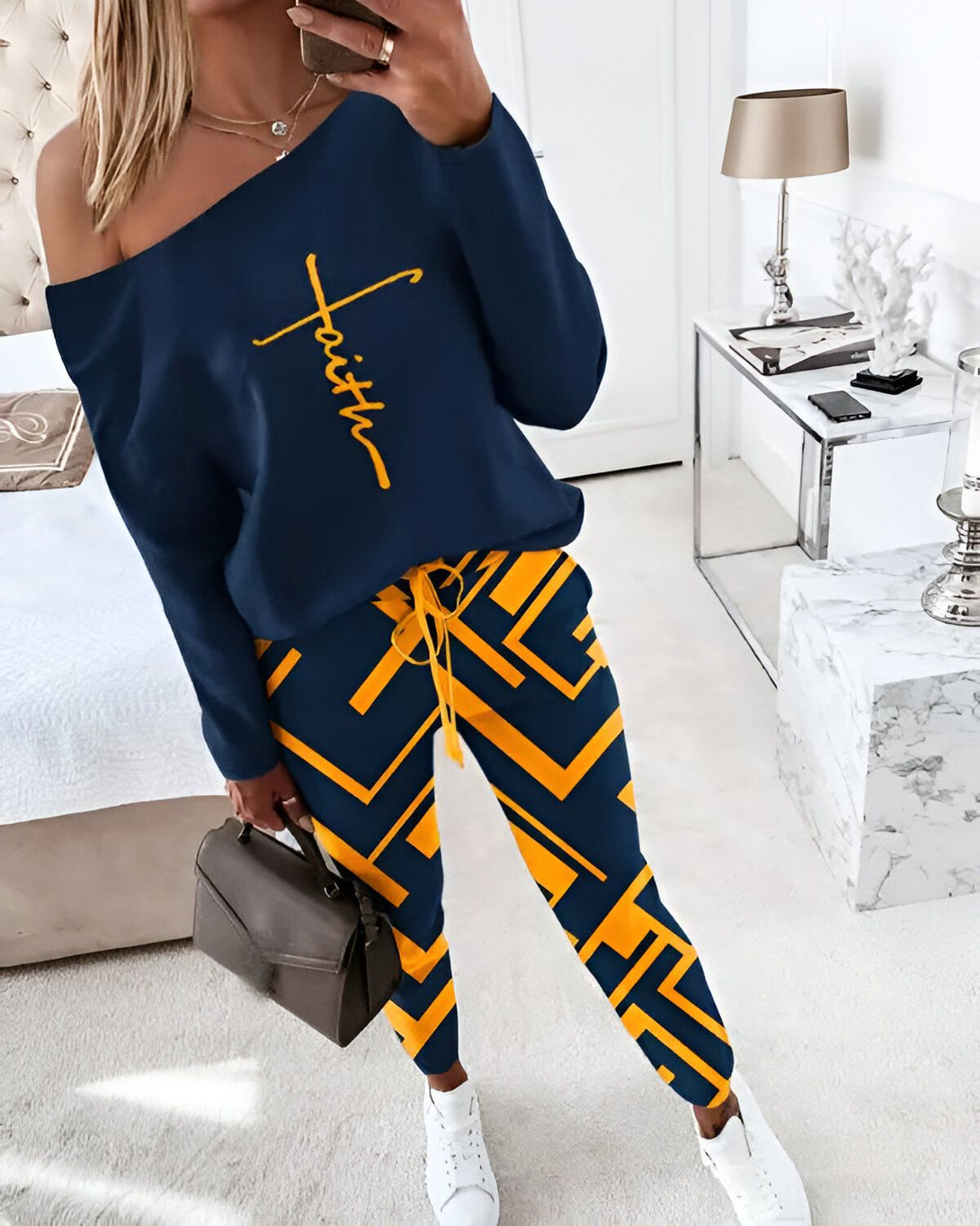 Une femme porte un ensemble de jogging bleu et jaune. Le haut est à épaules dénudées et le pantalon est à motifs géométriques.