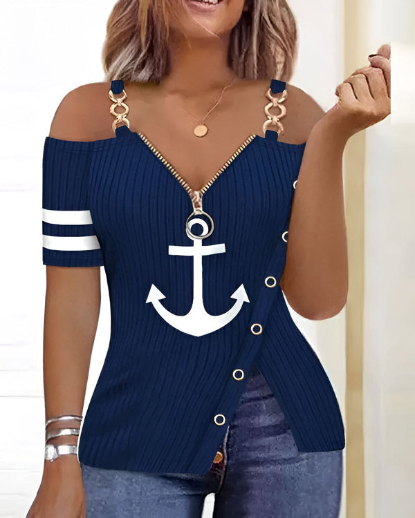 Une femme porte un débardeur bleu marine à épaules dénudées. Le débardeur est zippé sur le devant et a une ancre blanche imprimée sur la poitrine. La femme porte également un jean bleu et des talons hauts noirs.