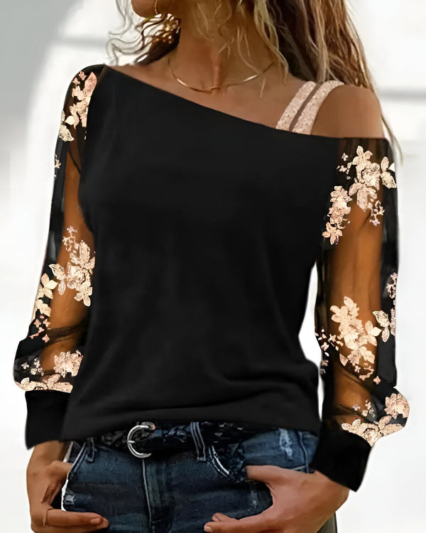 Une femme porte un haut noir à épaules dénudées avec des manches en résille brodées de fleurs dorées.