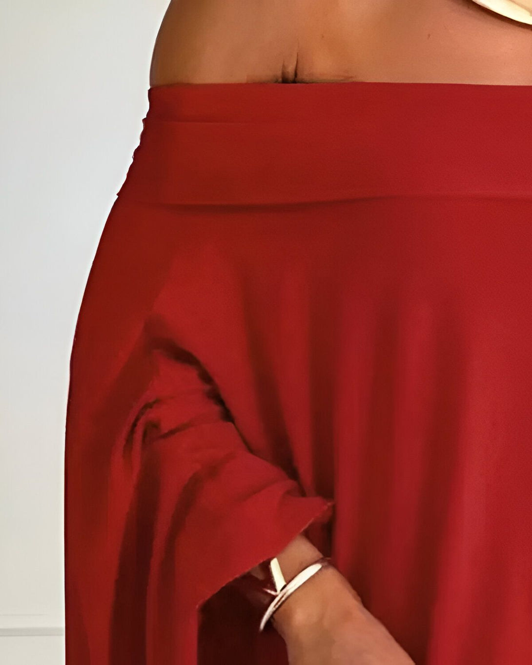 Une femme porte une longue jupe rouge fendue sur le côté. Elle est assortie d'un haut rouge à épaules dénudées.