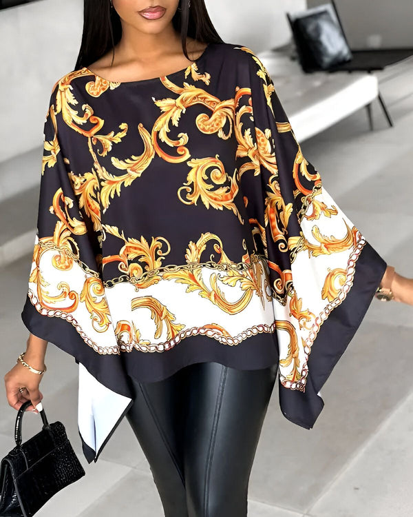 Une femme porte un chemisier noir et doré. Le chemisier est ample et a des manches chauve-souris. Il est également orné d'un motif floral doré. La femme porte un pantalon noir et des talons noirs. Elle a les cheveux longs et noirs et porte un maquillage léger.