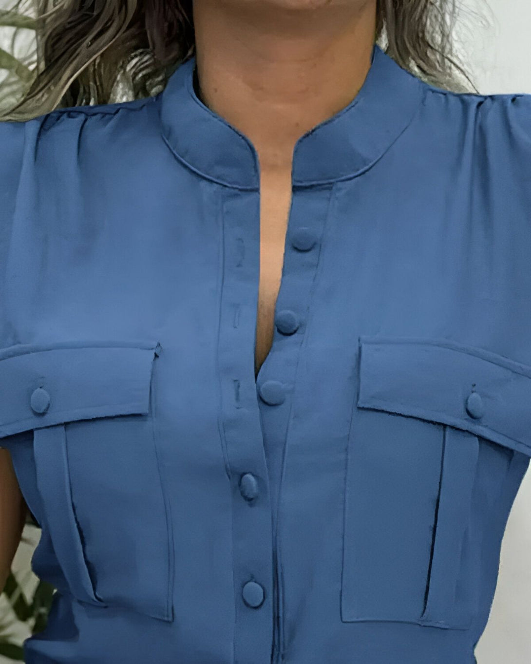 Une femme porte une chemisier bleu avec des boutons.
