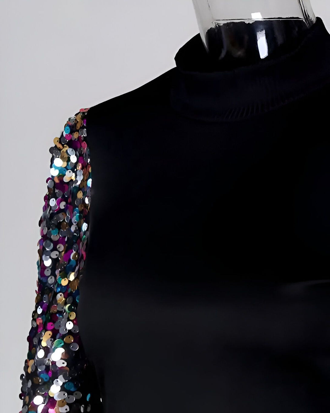 Une manche de vêtement de couleur noire est recouverte de paillettes multicolores.