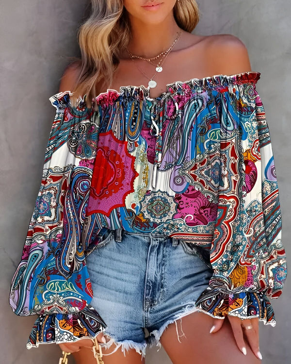 Une femme porte un chemisier à épaules dénudées avec un motif cachemire coloré. Le chemisier est associé à un short en jean bleu.