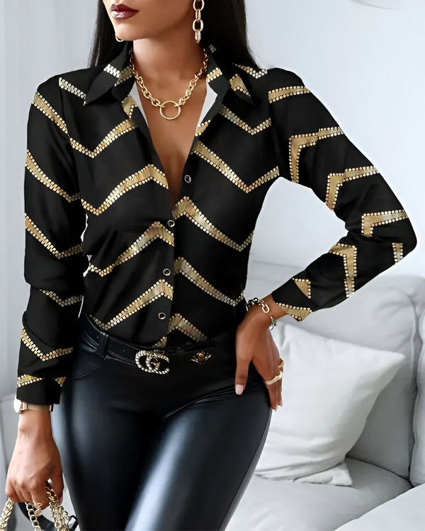 Une femme porte une chemise noire et dorée. La chemise est ouverte et on peut voir son décolleté. Elle porte également un pantalon noir et des talons noirs.