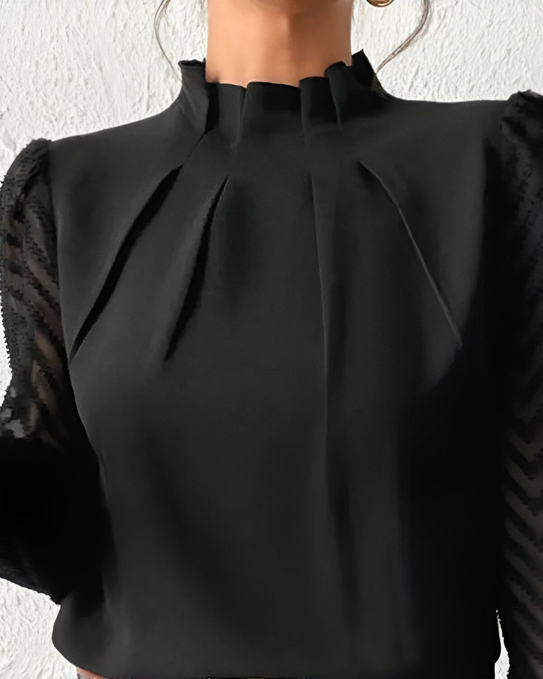 Une image d'une femme portant un chemisier noir à col montant et à manches longues bouffantes. Le chemisier est en mousseline de soie et présente un motif zébré sur les manches.