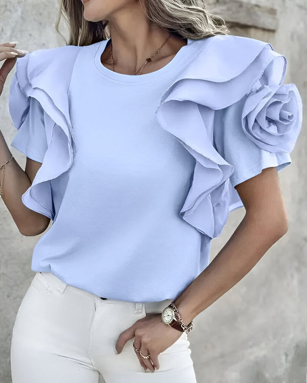 Une femme porte un chemisier bleu clair à volants avec un jean blanc.