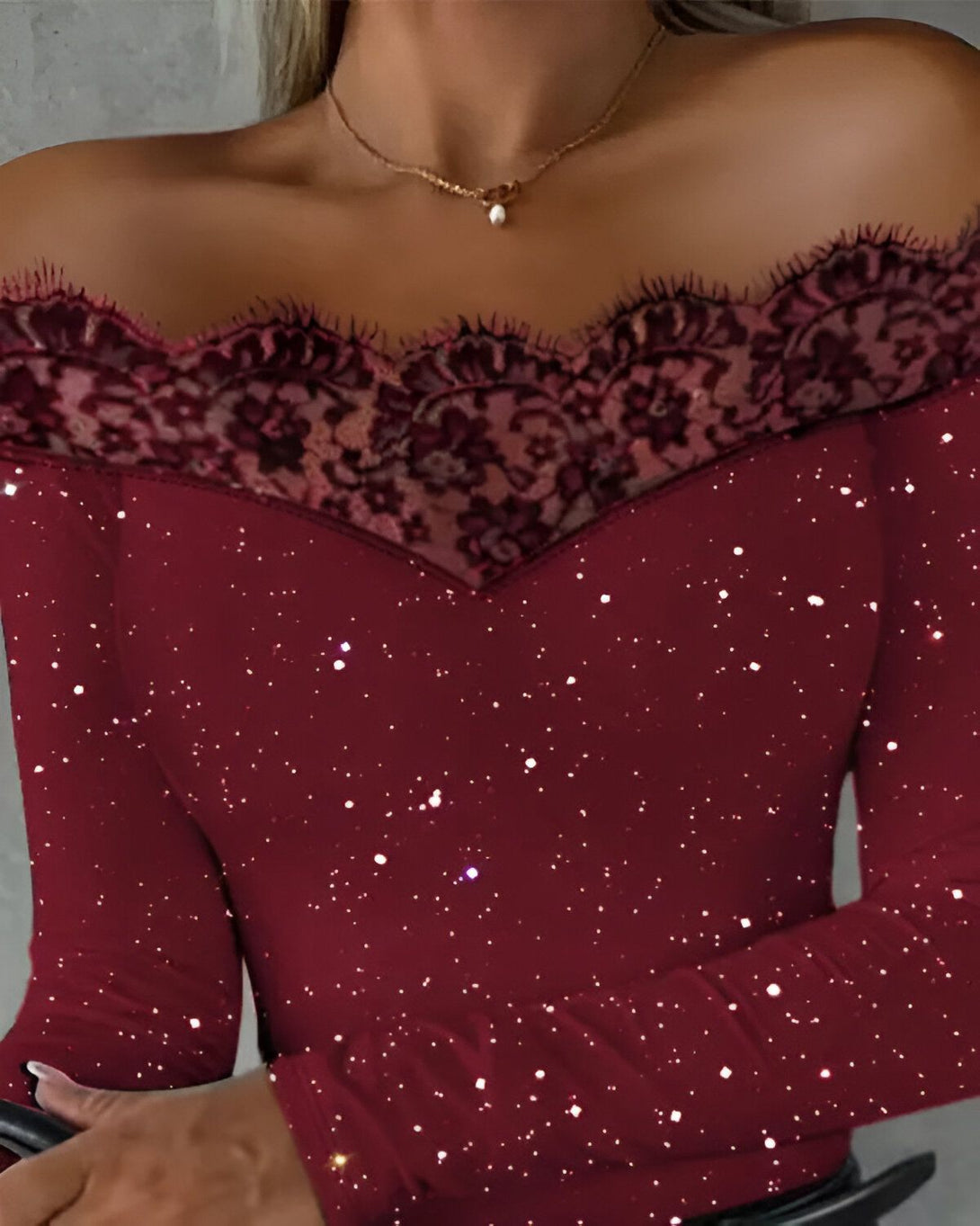 Une femme porte un haut rouge à épaules dénudées avec des manches longues et une bordure en dentelle noire.