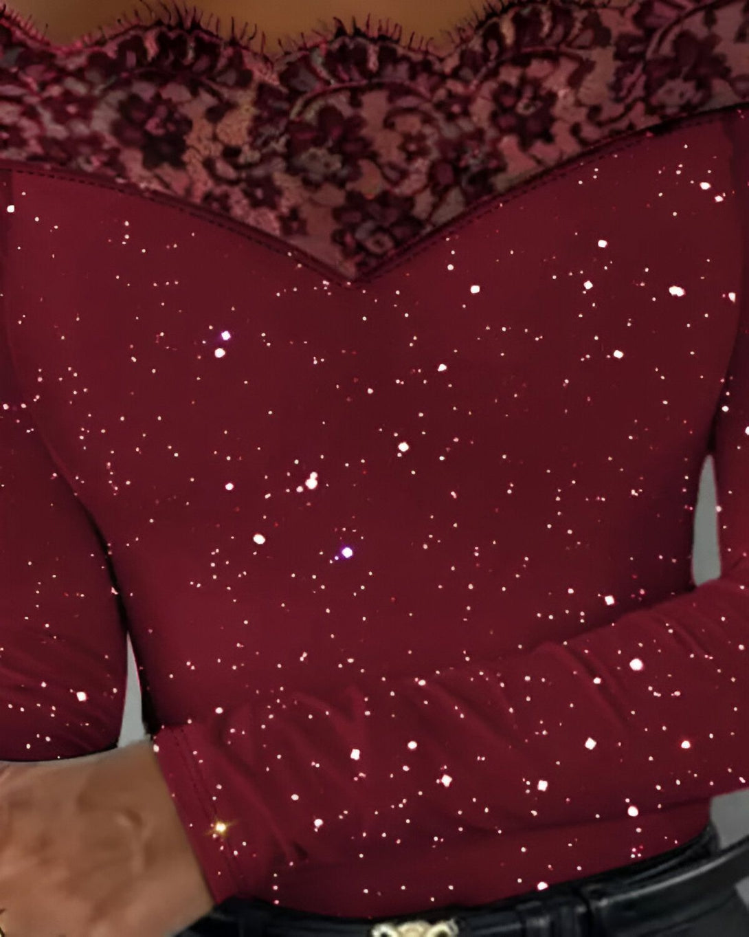 Le haut est rouge et scintillant avec des manches longues et un col en dentelle noire.