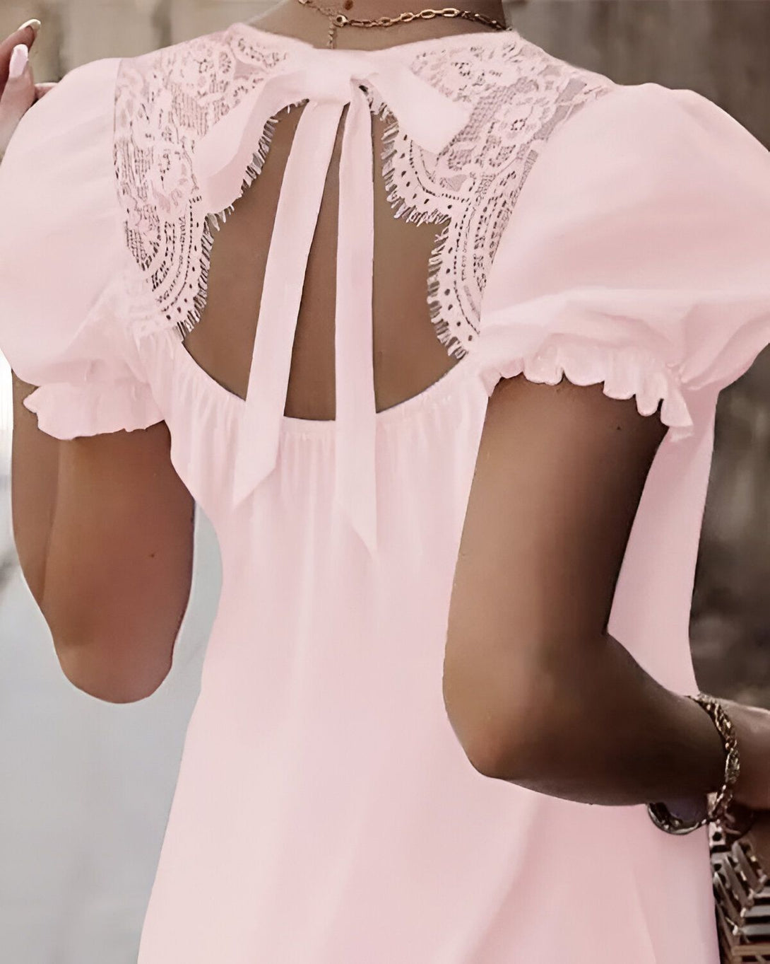 Une femme porte une robe rose dos nu avec un laçage.