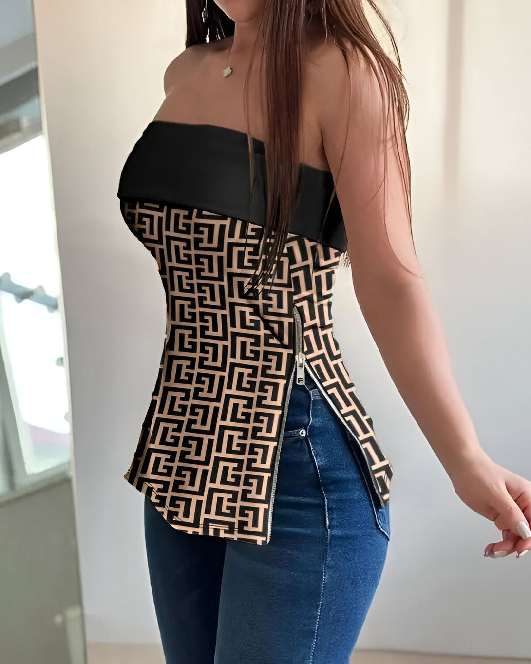 Une jeune femme porte un corset marron et noir à motifs géométriques et un jean bleu.