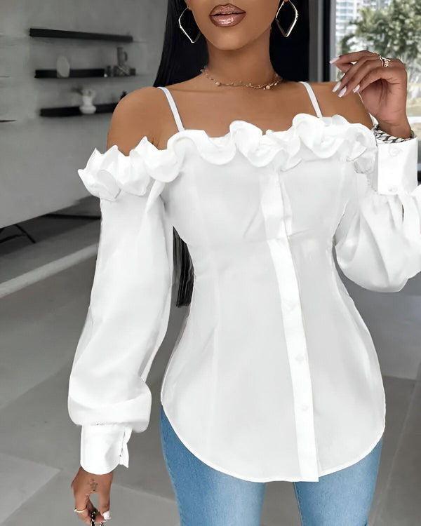 Une femme porte un chemisier blanc à épaules dénudées. Le chemisier est en mousseline de soie et comporte des volants sur les épaules. Il est associé à un jean bleu.