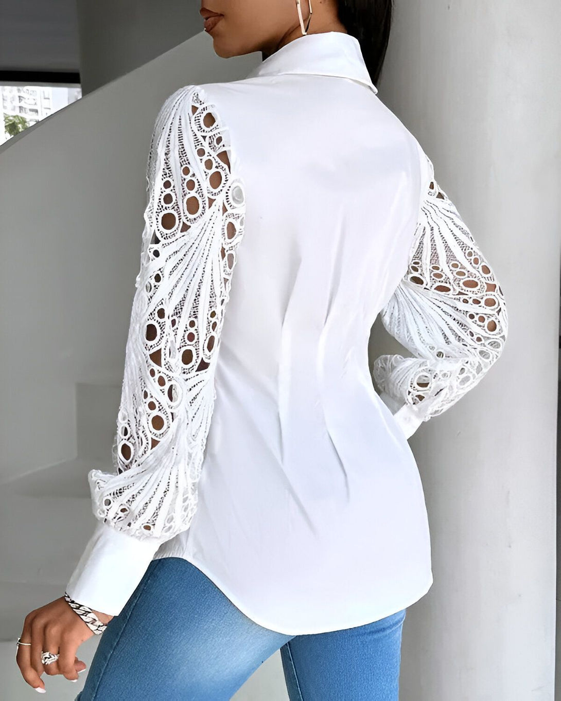 Une femme porte une chemise blanche en dentelle. La chemise est ouverte dans le dos et les manches sont bouffantes.