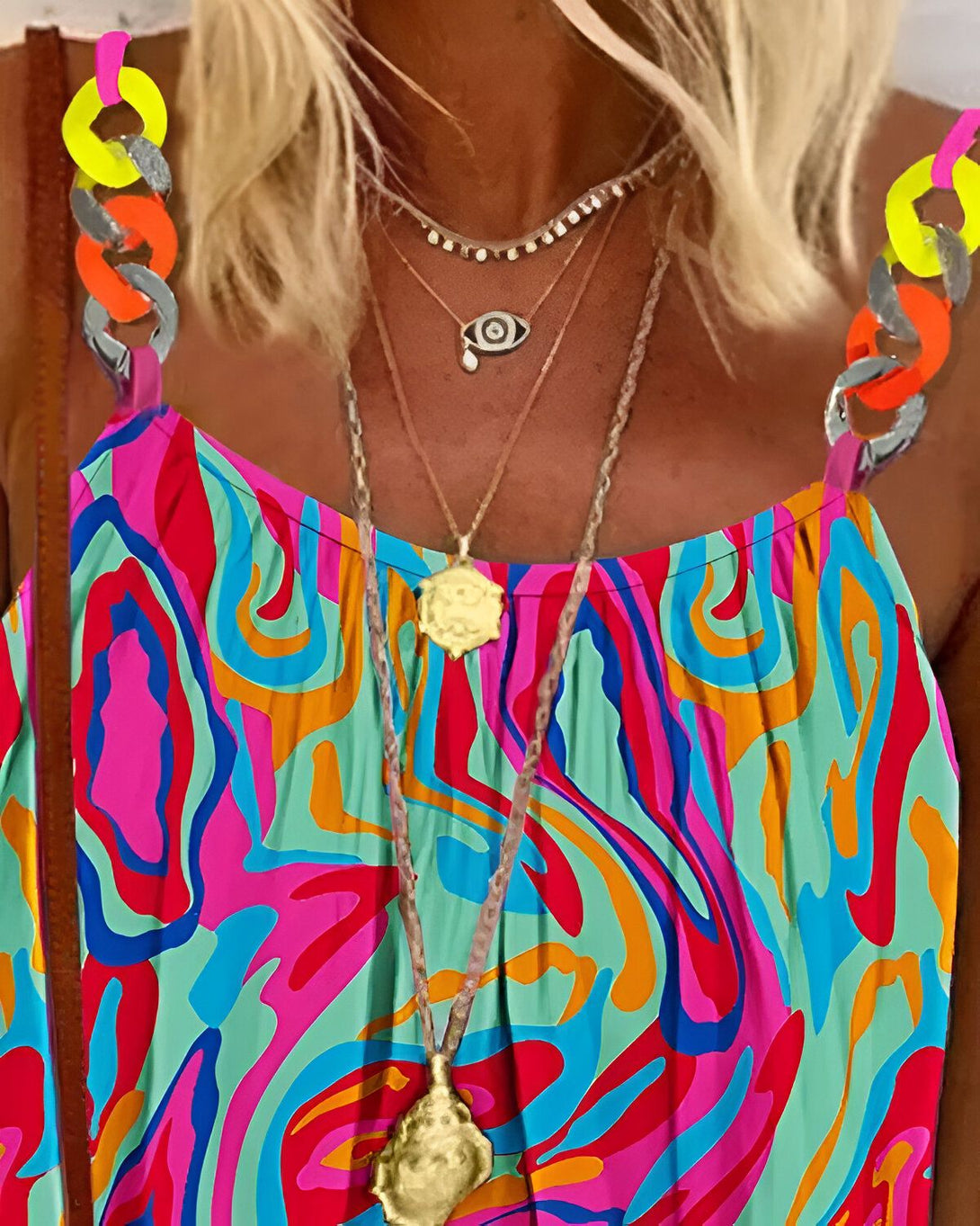 Une femme porte une robe colorée à motifs et des colliers.
