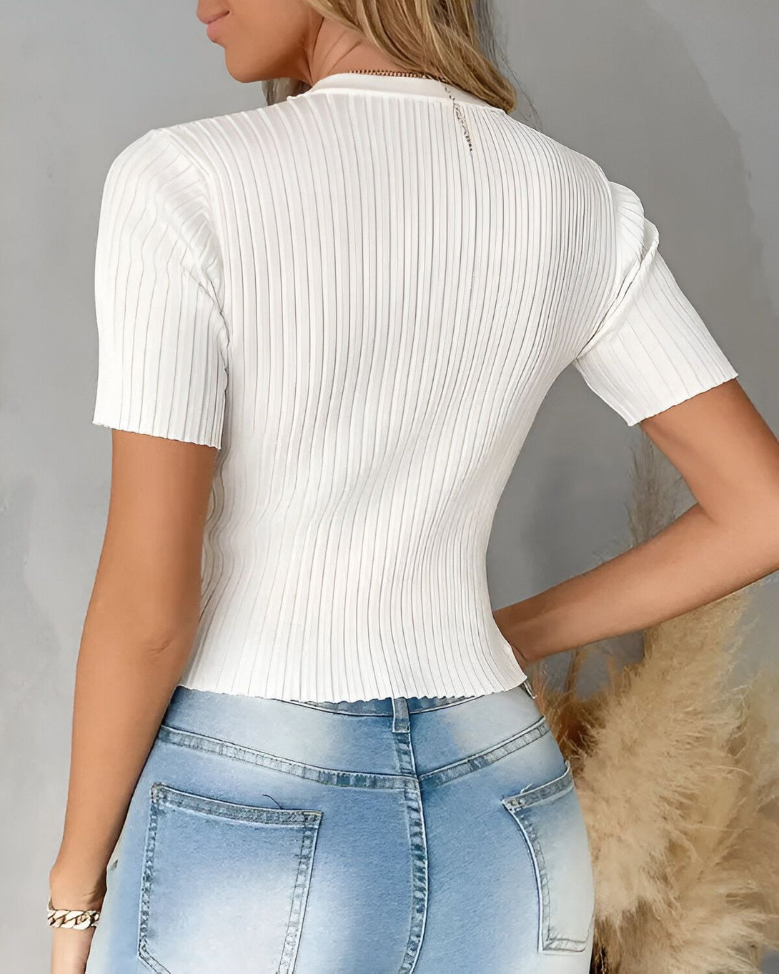 Une femme porte un t-shirt blanc côtelé à manches courtes et un jean bleu.