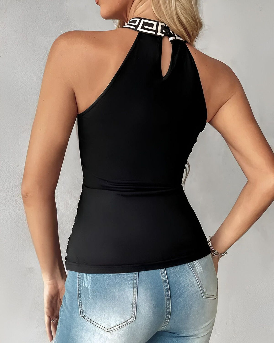 Une femme porte un haut noir avec un col montant et un pantalon en jean bleu.