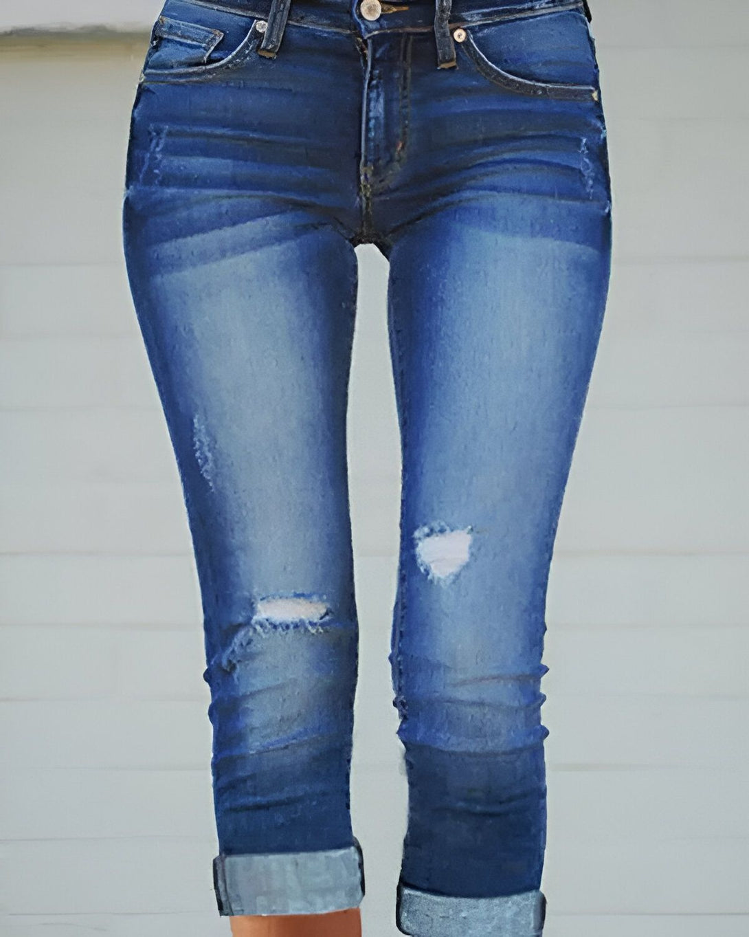 Une image d'une femme portant un jean bleu moulant déchiré au niveau des genoux.