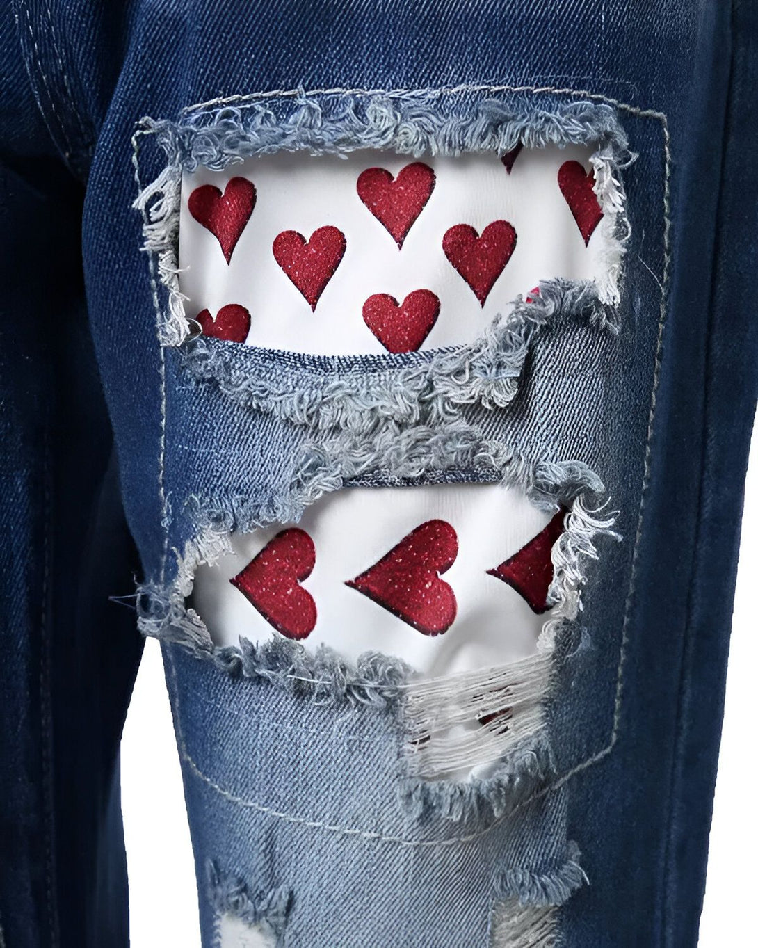Le jean troué est déchiré au niveau des genoux avec un tissu en dessous avec des coeurs rouges sur fond blanc.