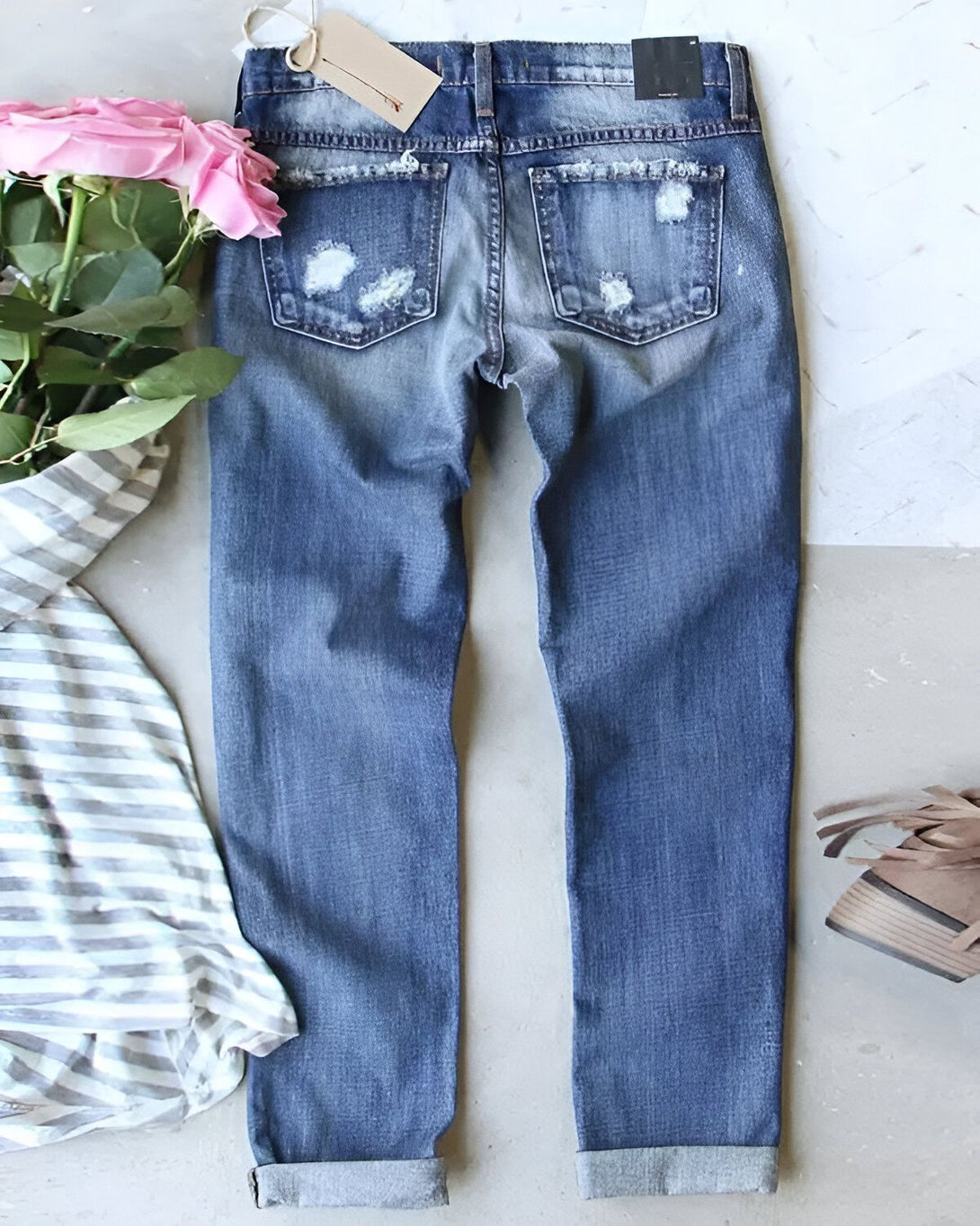 Une image de jeans bleu déchirés avec des roses roses et des chaussures marron clair à côté.