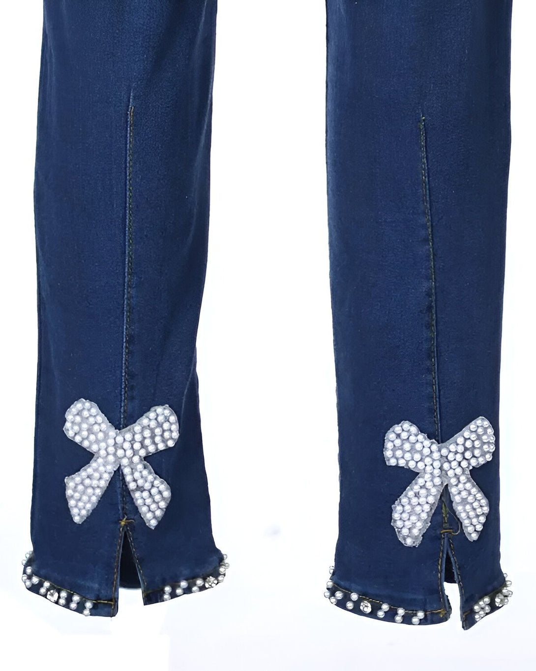 Le bas des jambes d'un jean bleu avec des nœuds en perles blanches sur les côtés.
