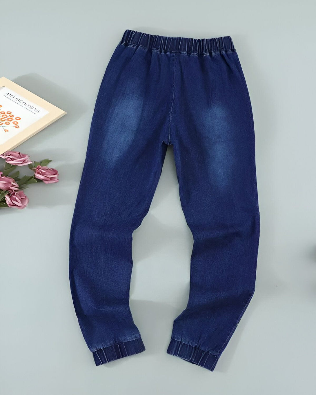 Une image d'un jean bleu marine pour enfant avec une taille élastiquée et des chevilles resserrées.