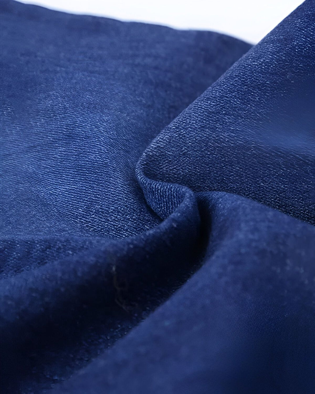 Une image en gros plan d'un tissu denim bleu. Le tissu est froissé et on peut voir les détails de la texture.
