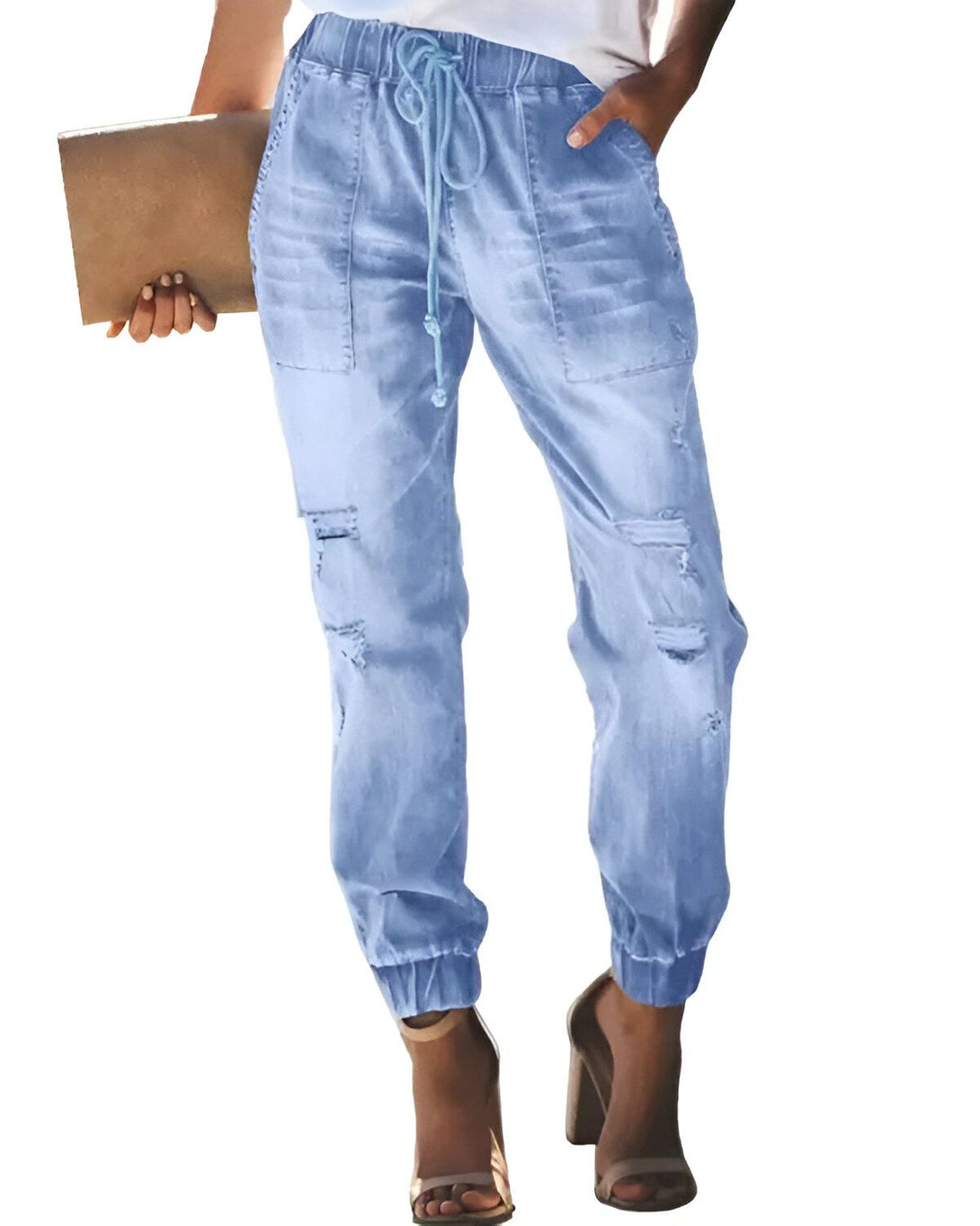 Une femme porte un jean bleu clair déchiré et troué au niveau des genoux. Le jean est taille haute et possède une ceinture à nouer. La femme porte également des sandales à talons hauts de couleur marron.