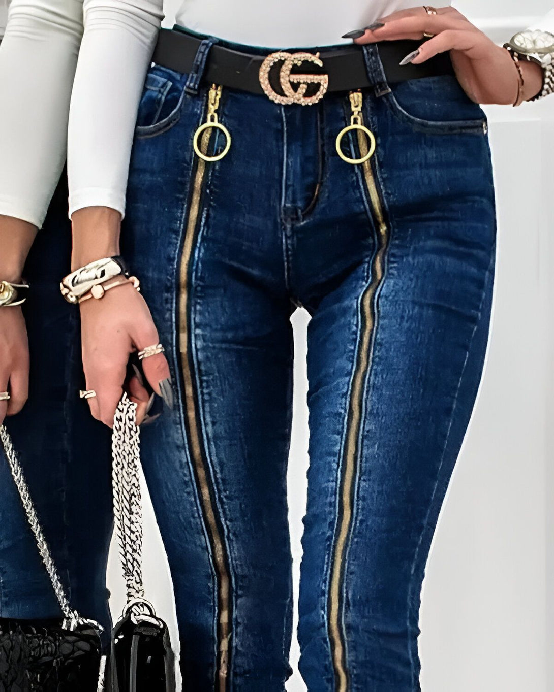 Une image de deux femmes portant des jeans bleus avec des fermetures éclair dorées sur les côtés. Les femmes portent également des talons hauts noirs et des chemises blanches.