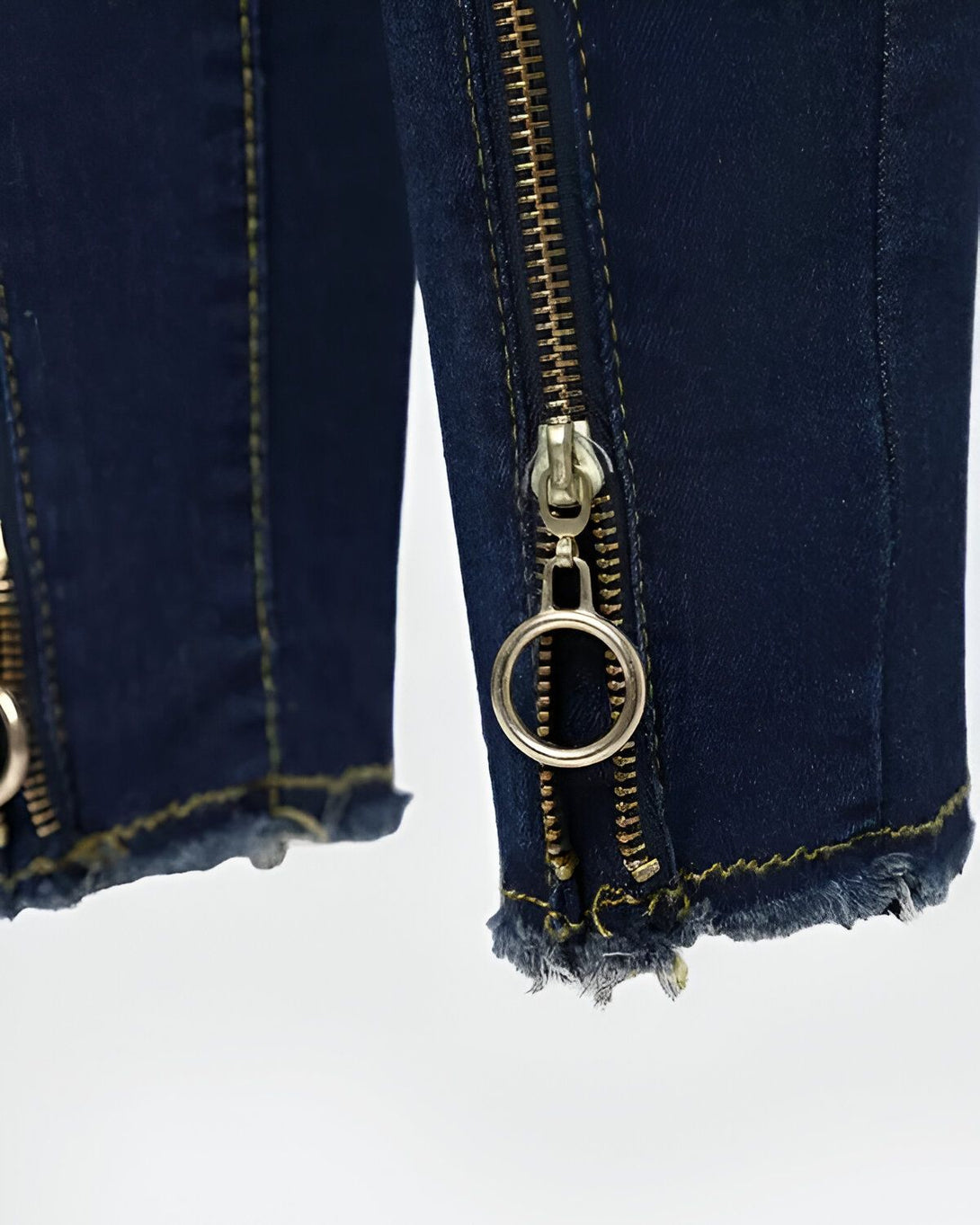 Une image de jeans bleus avec des fermetures éclair dorées et des anneaux.