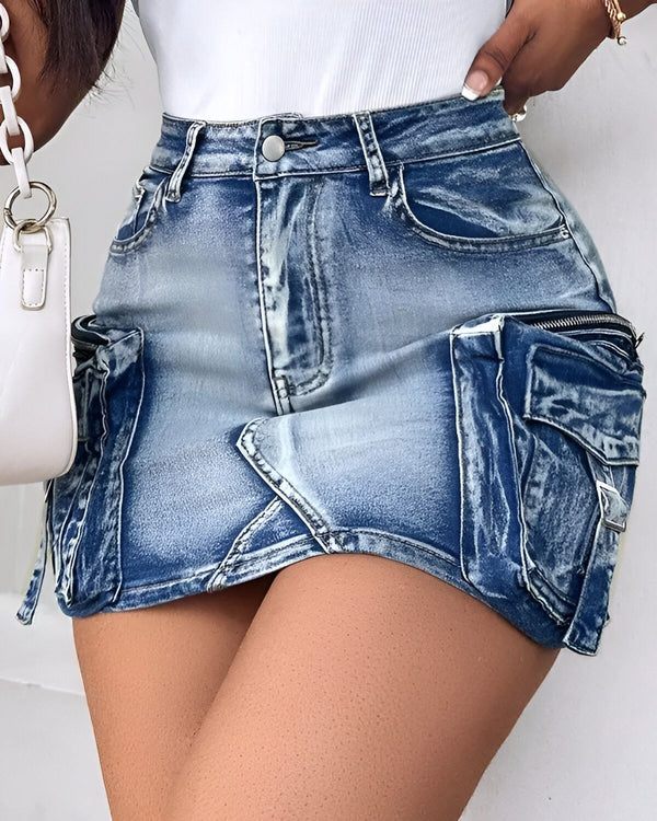 Une jeune femme porte une jupe en jean bleu clair taille haute. La jupe est courte et possède des poches cargo sur les côtés. La femme est vue de dos et porte un haut blanc.