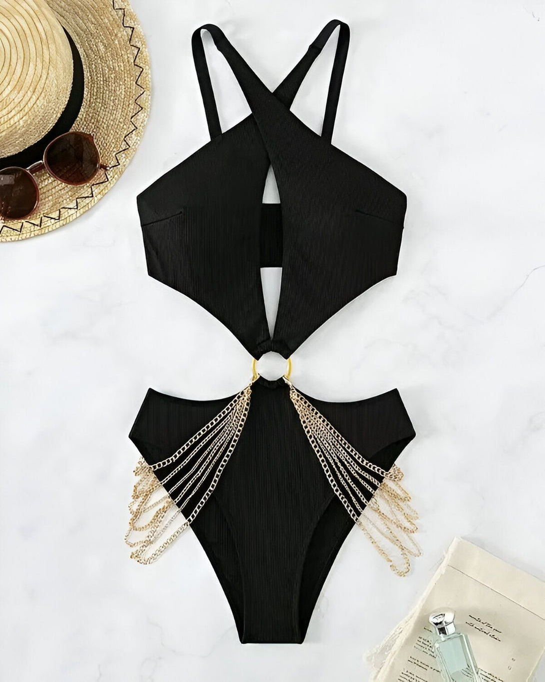 Une image d'un maillot de bain une pièce noir avec des chaînes dorées sur les côtés. Le maillot de bain est dos nu et a une encolure croisée.