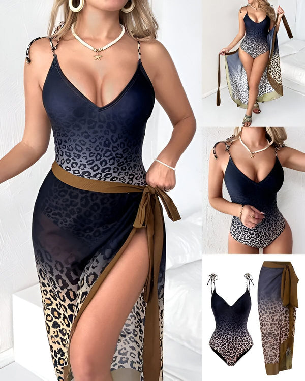 Une femme porte un maillot de bain une pièce noir et marron avec un décolleté plongeant et des bretelles fines. Le maillot de bain est également doté d'une ceinture à nouer à la taille et d'une longue fente sur le côté. La femme porte également un paréo assorti.