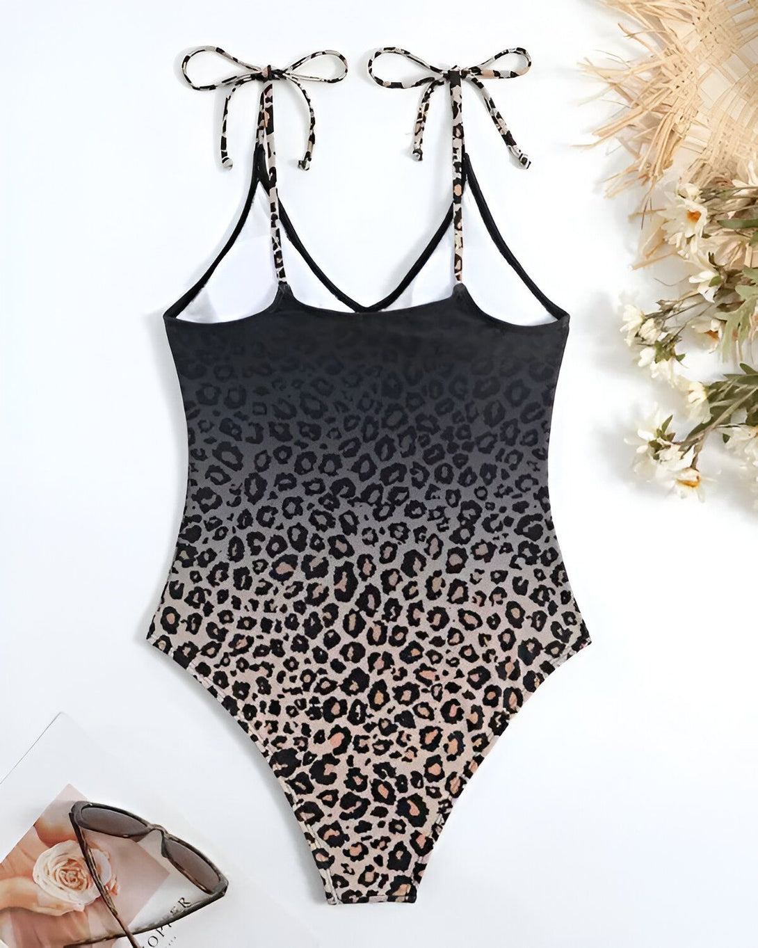 Un maillot de bain une pièce avec un imprimé léopard marron et noir. Le maillot de bain a un dos nageur et des bretelles fines.