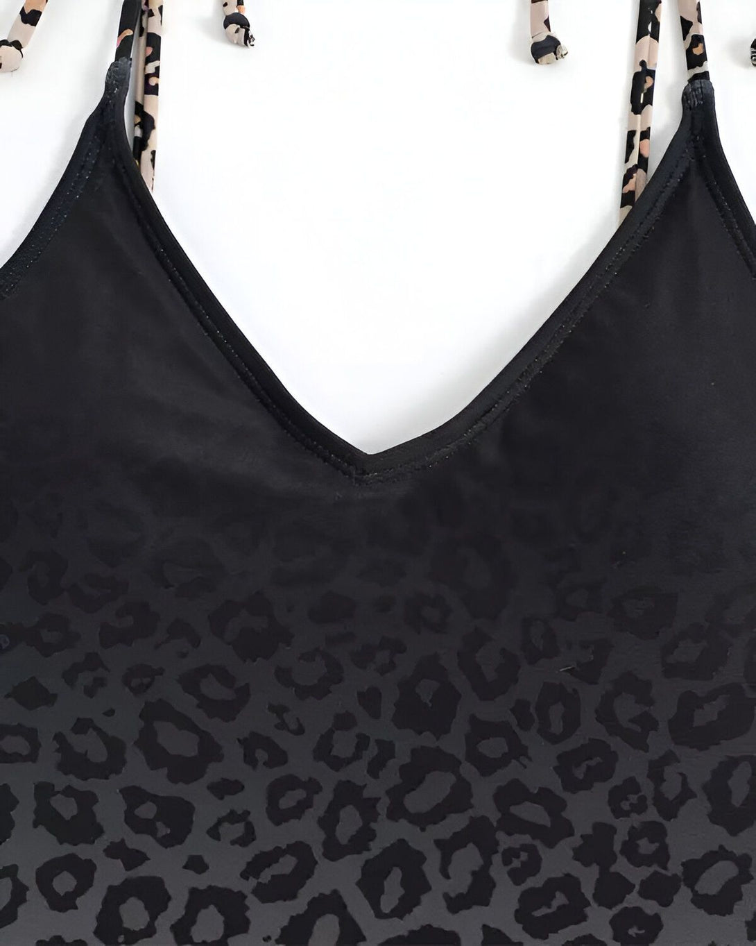 Un maillot de bain une pièce noir avec un imprimé léopard. Le maillot de bain est dos nu et possède des bretelles fines.