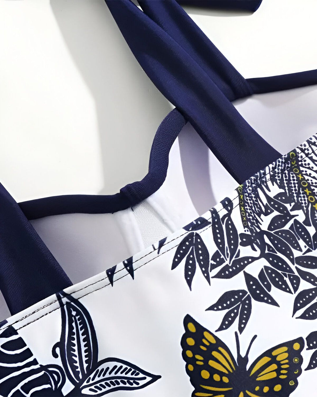 Une image d'un maillot de bain une pièce avec un imprimé floral et des bretelles bleu marine.