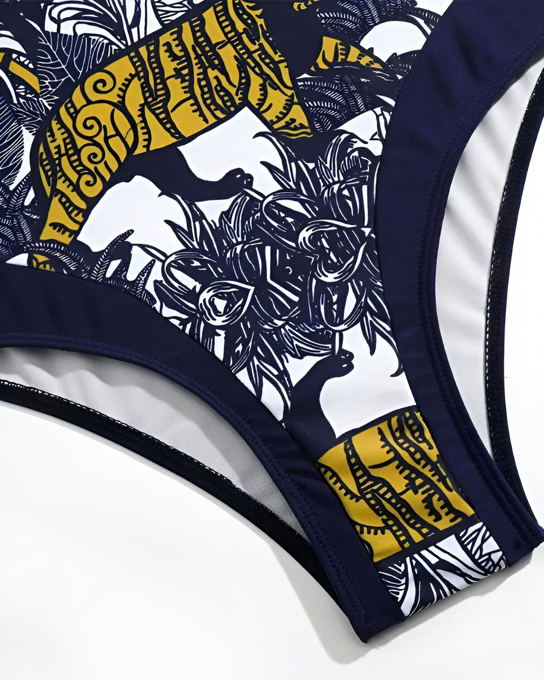 Le bas d'un maillot de bain une pièce de couleur bleu marine avec un motif de feuilles tropicales jaunes et blanches.