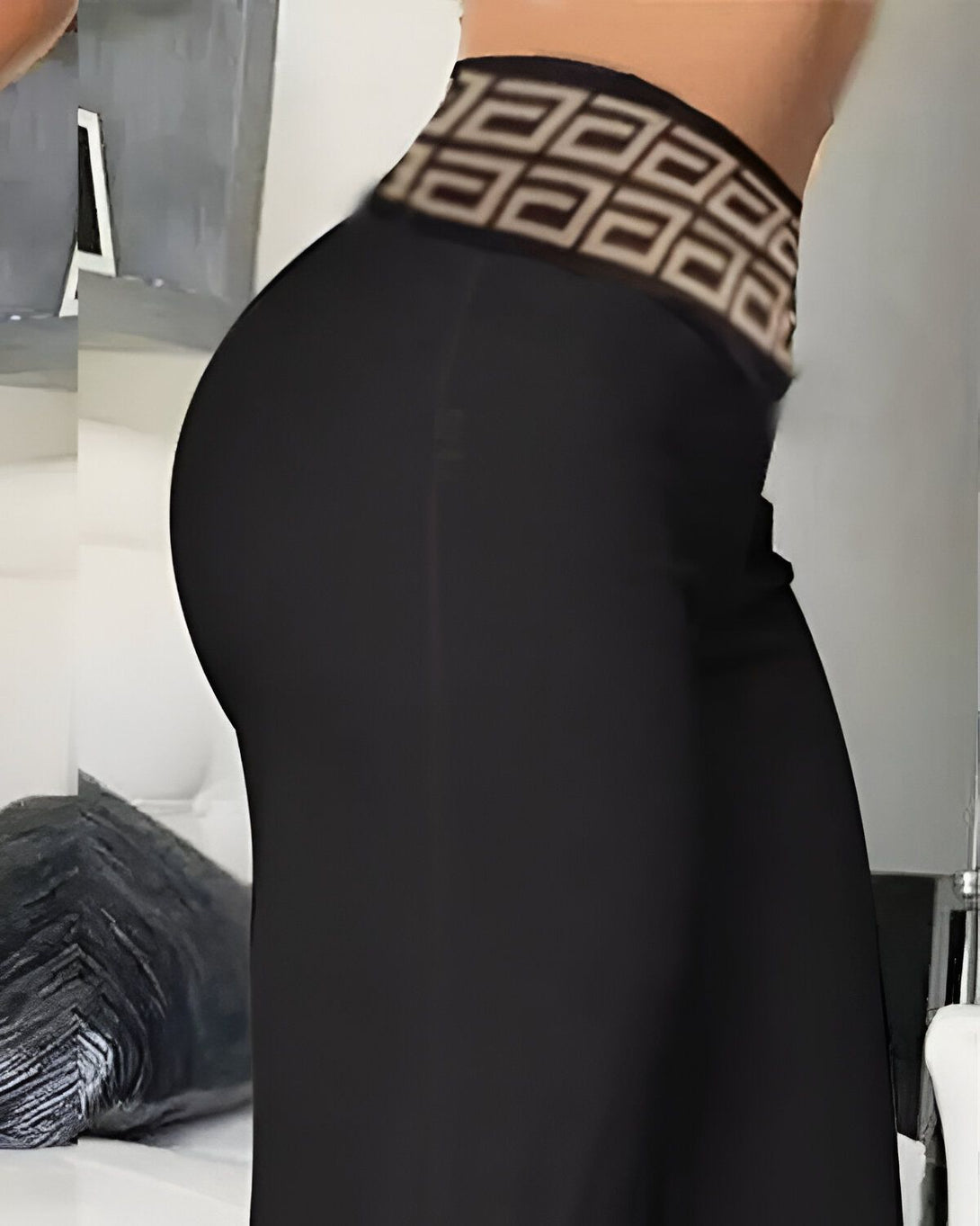 Une femme porte un legging noir moulant taille haute avec un motif marron.