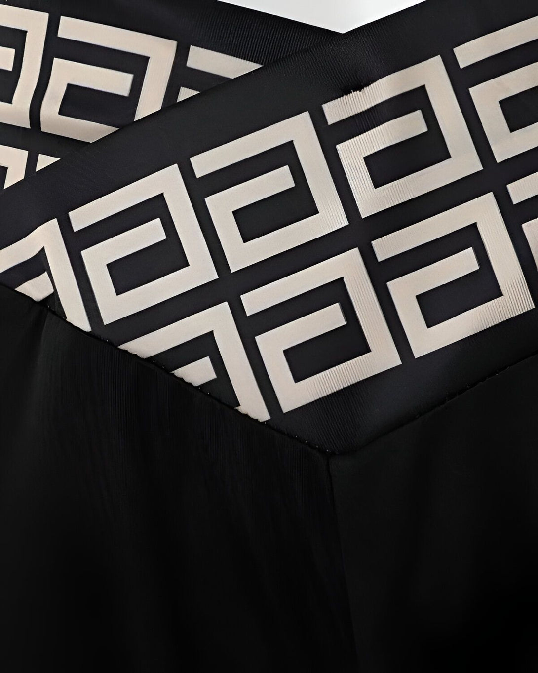 Une image en gros plan d'un tissu noir avec un motif géométrique beige.