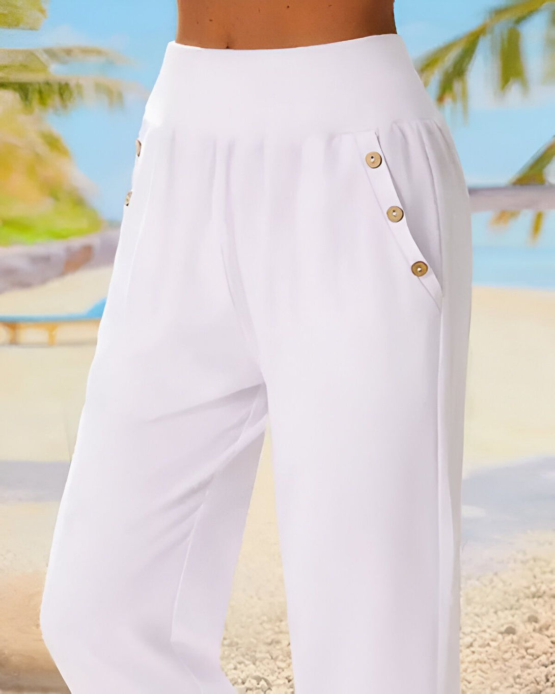 Une femme porte un pantalon blanc ample avec des boutons sur le côté. Le pantalon est taille haute et a une coupe droite. La femme est debout sur une plage, avec des palmiers en arrière-plan.