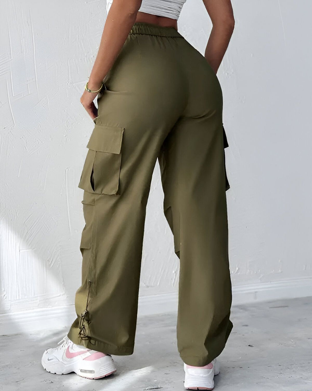 Une femme porte un pantalon cargo vert olive taille haute avec des poches sur les côtés. Elle est vue de dos.