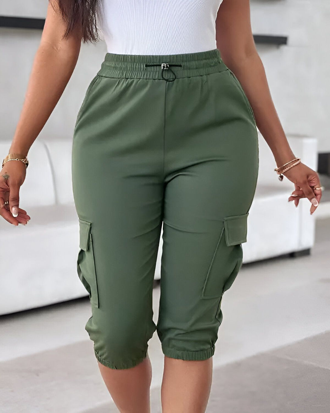 Une femme porte un pantalon cargo vert olive taille haute avec des poches cargo sur les côtés. Le pantalon est ample et confortable, et il est parfait pour les activités décontractées.