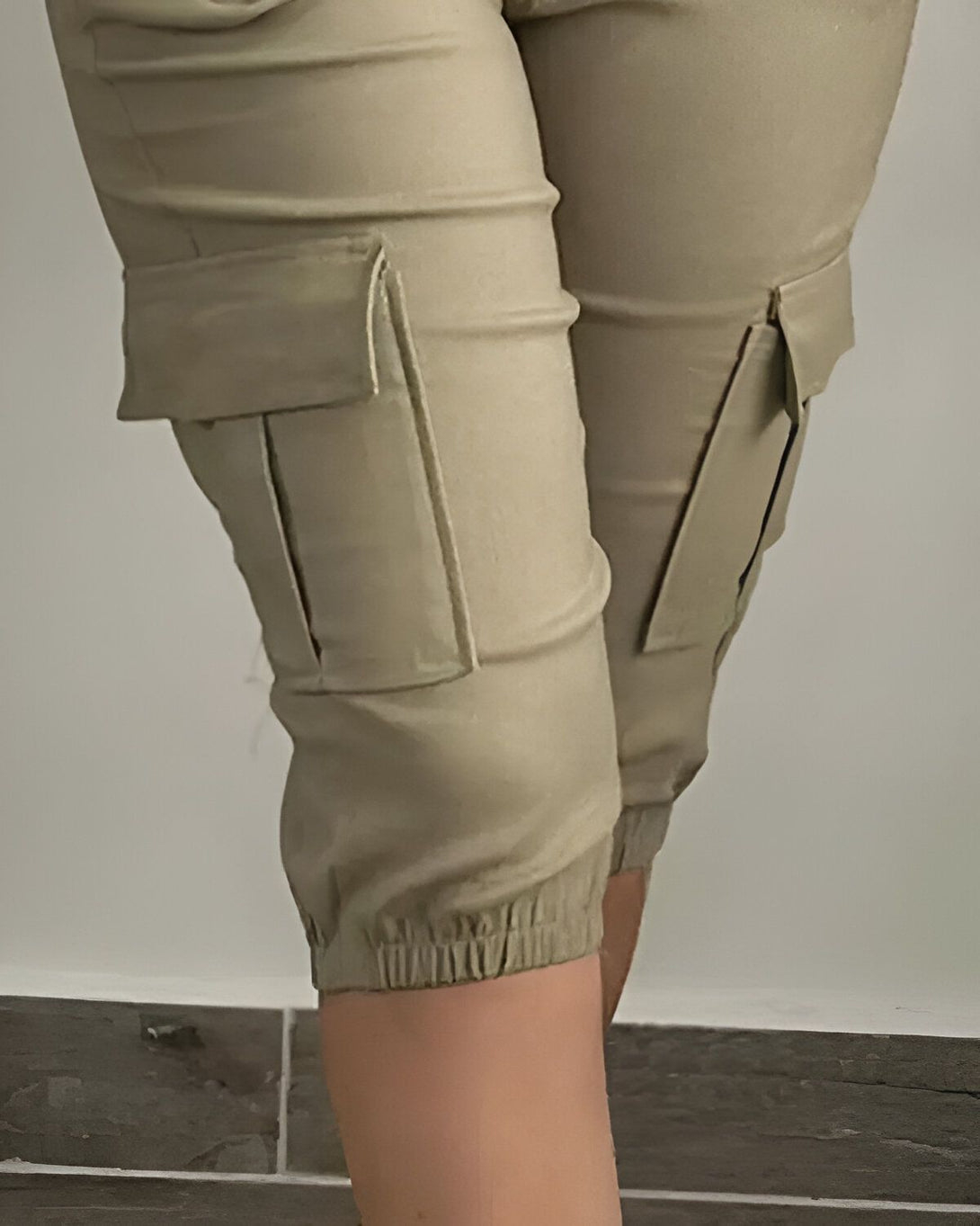 Une image d'un mannequin portant un pantalon cargo kaki. Le pantalon est ample et a des poches sur les côtés. Le mannequin est vu de côté et porte également un haut kaki.
