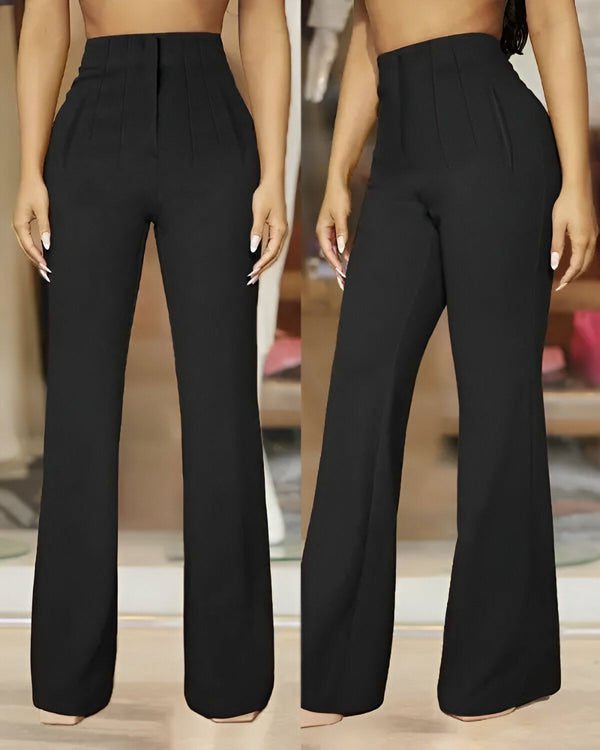 Une femme porte un pantalon taille haute noir. Le pantalon est large et évasé. Il est porté avec une chemise blanche et des talons noirs.