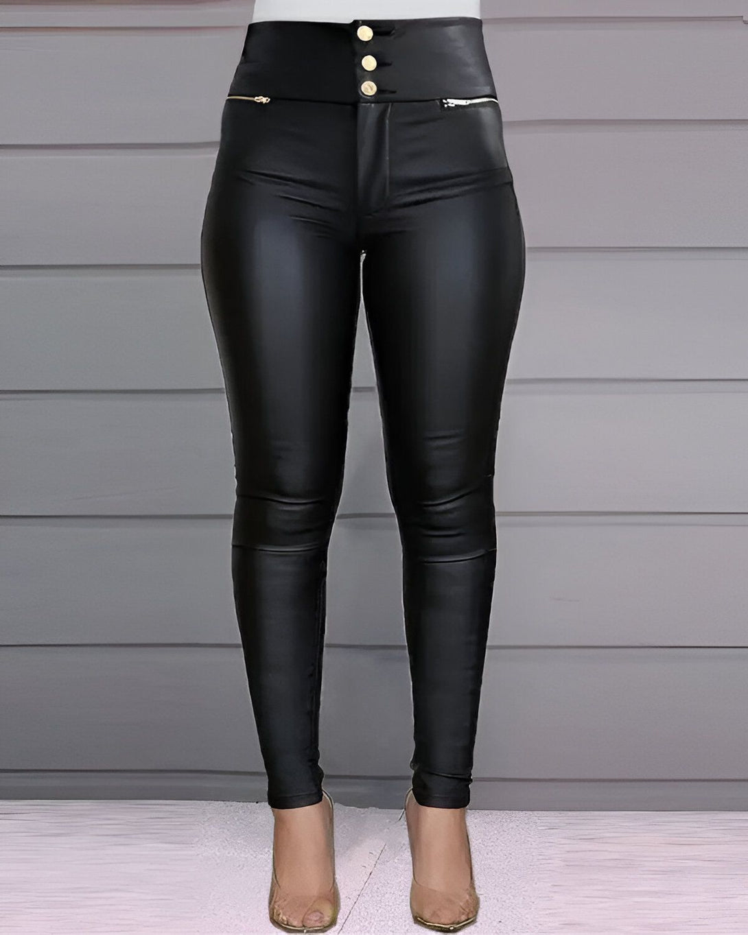 Une femme porte un jean en simili cuir noir moulant taille haute avec des boutons dorés.