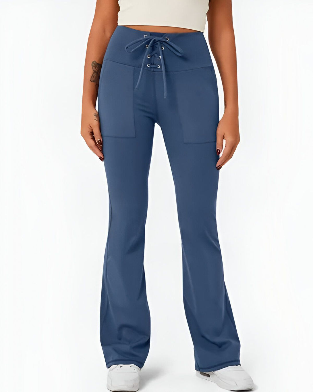 Une femme porte un pantalon de yoga bleu marine taille haute avec un laçage à la taille. Le pantalon est évasé et possède des poches.