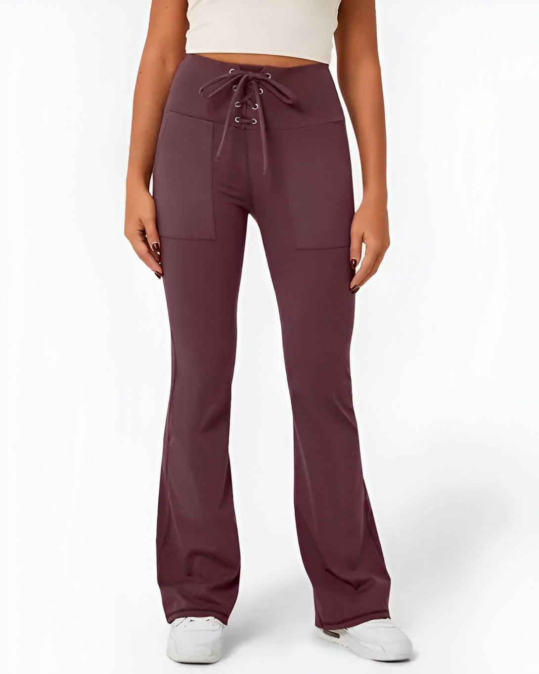 Une femme porte un pantalon de yoga évasé marron avec un laçage à la taille.