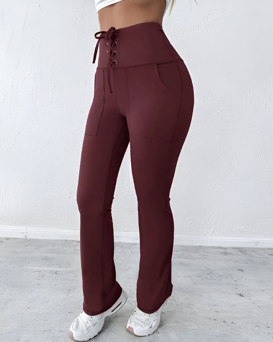 Une femme porte un pantalon marron moulant taille haute avec un laçage à la taille.