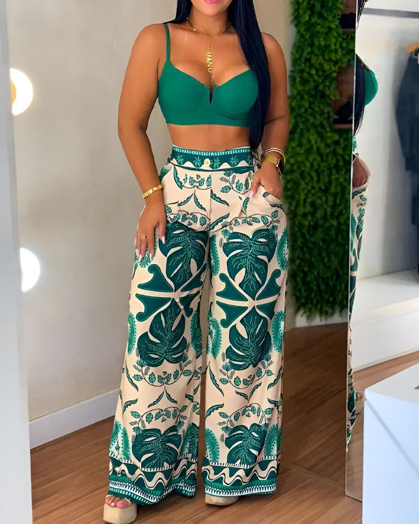 Une femme porte un pantalon taille haute vert et beige à motif de feuilles tropicales. Elle porte également un soutien-gorge vert.