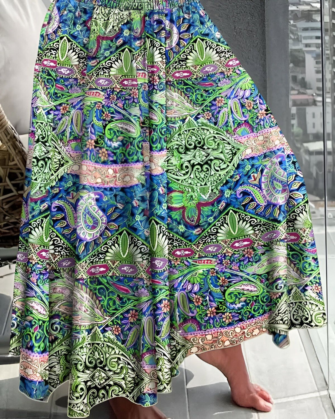 Une femme porte une jupe longue colorée avec un motif floral et des détails paisley.